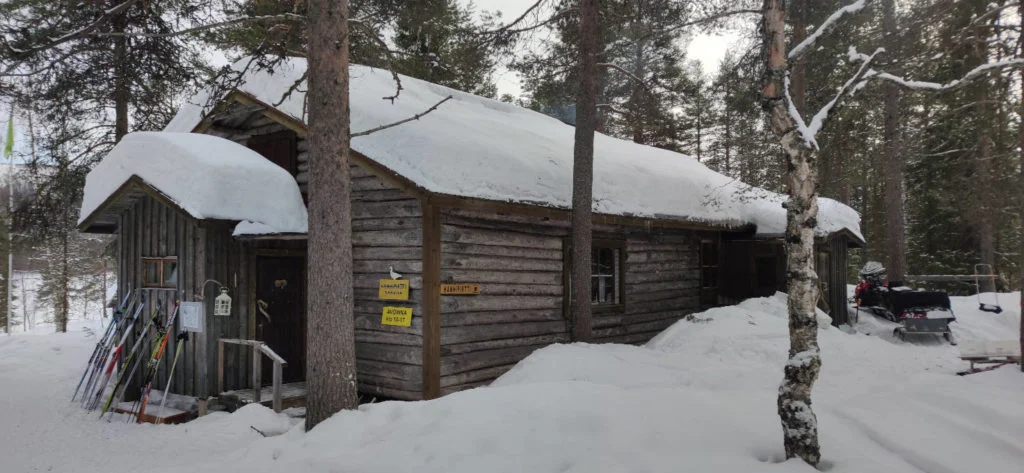 Hanhipirtti latukahvila ulkoa – vanha hirsirakennus lumisessa metsässä Levillä